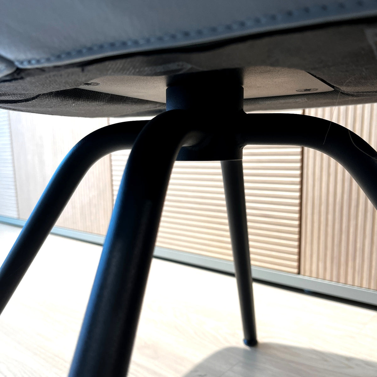 Unterseite des WK 722 Armlehnstuhls mit zentraler Befestigung und vier gebogenen schwarzen Metallbeinen